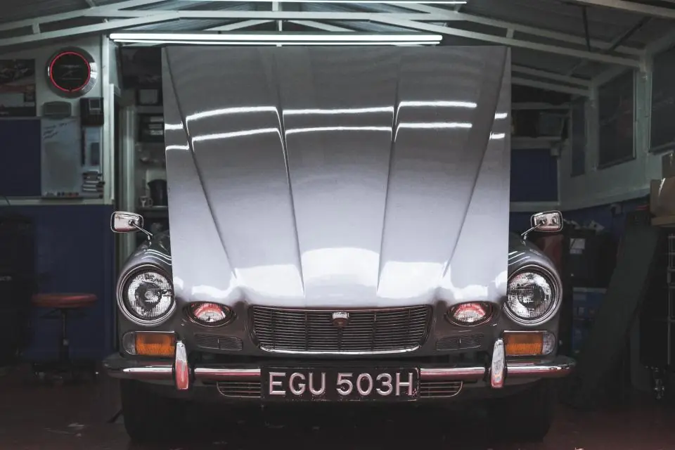 Classic car with its hood open in a repair garage