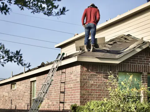 Roofer inspecting a roof on a brick home